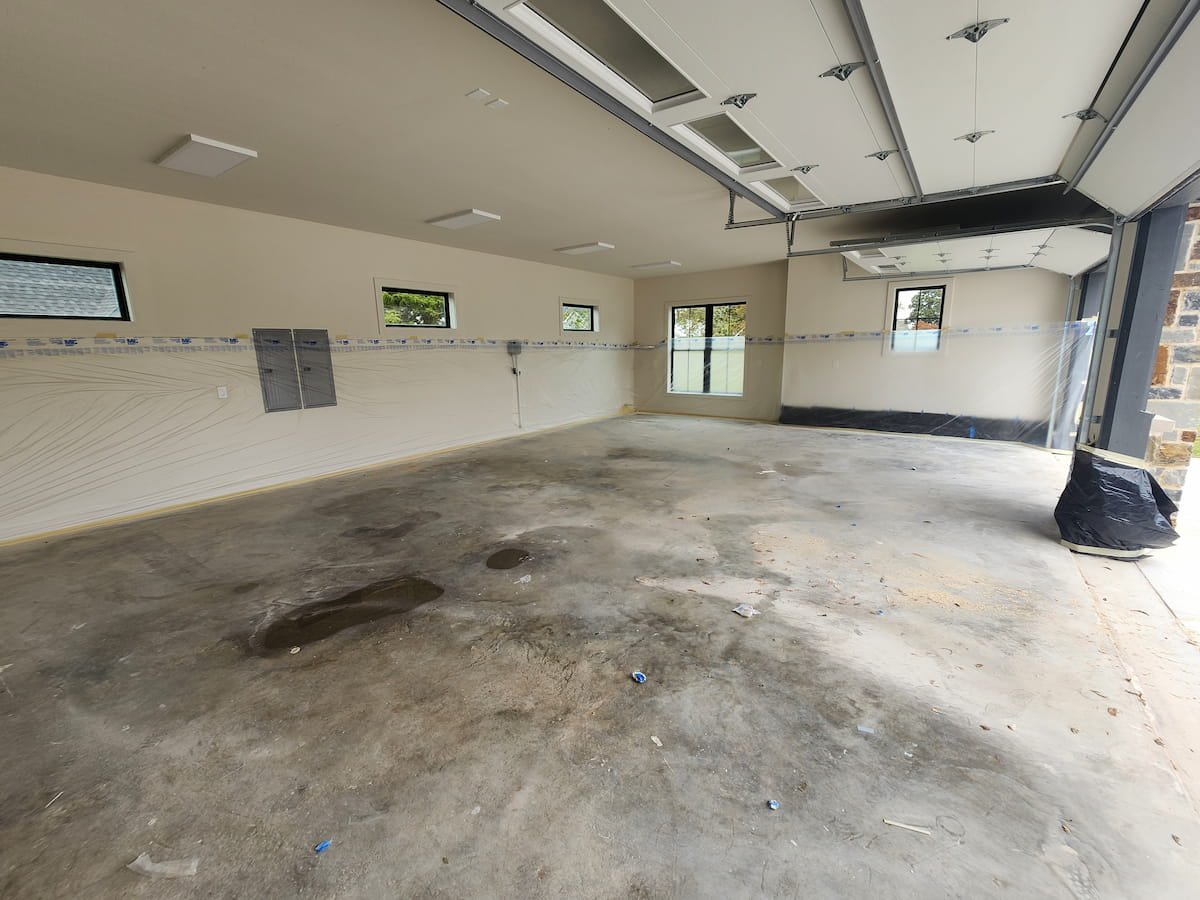 Post construction garage floor in Corsicana TX covered in heavy drywall dust mud and construction grime before cleaning