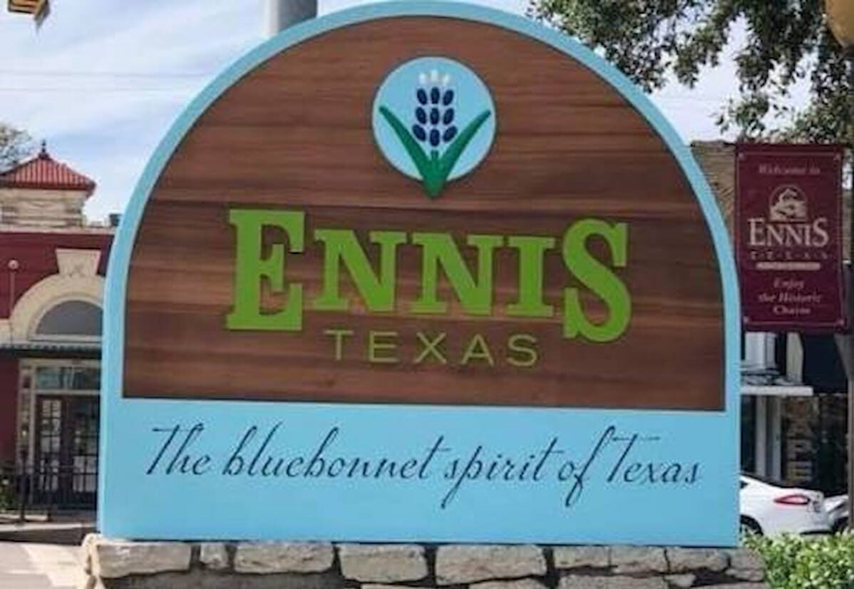 Welcome to Ennis, Texas sign featuring the Bluebonnet Spirit of Texas slogan in historic downtown Ennis, TX.