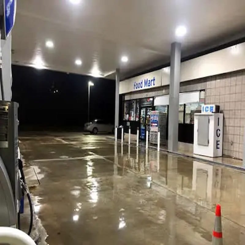 Clean, wet concrete parking pad outside a commercial gas station at night.